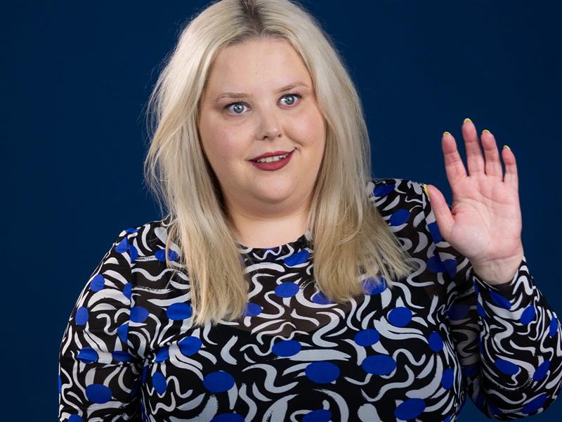 Comedian Mish Wittrup smiling and waving