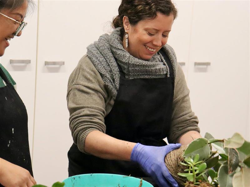 A student and Lilian wrapping a Kokedama in String