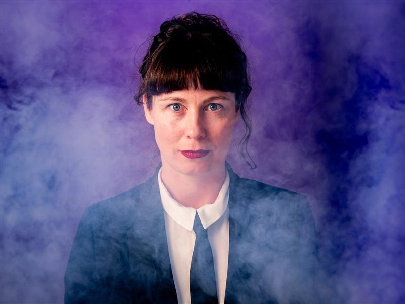 Comedian Alanta Colley in a suit, looking seriously into the camera.